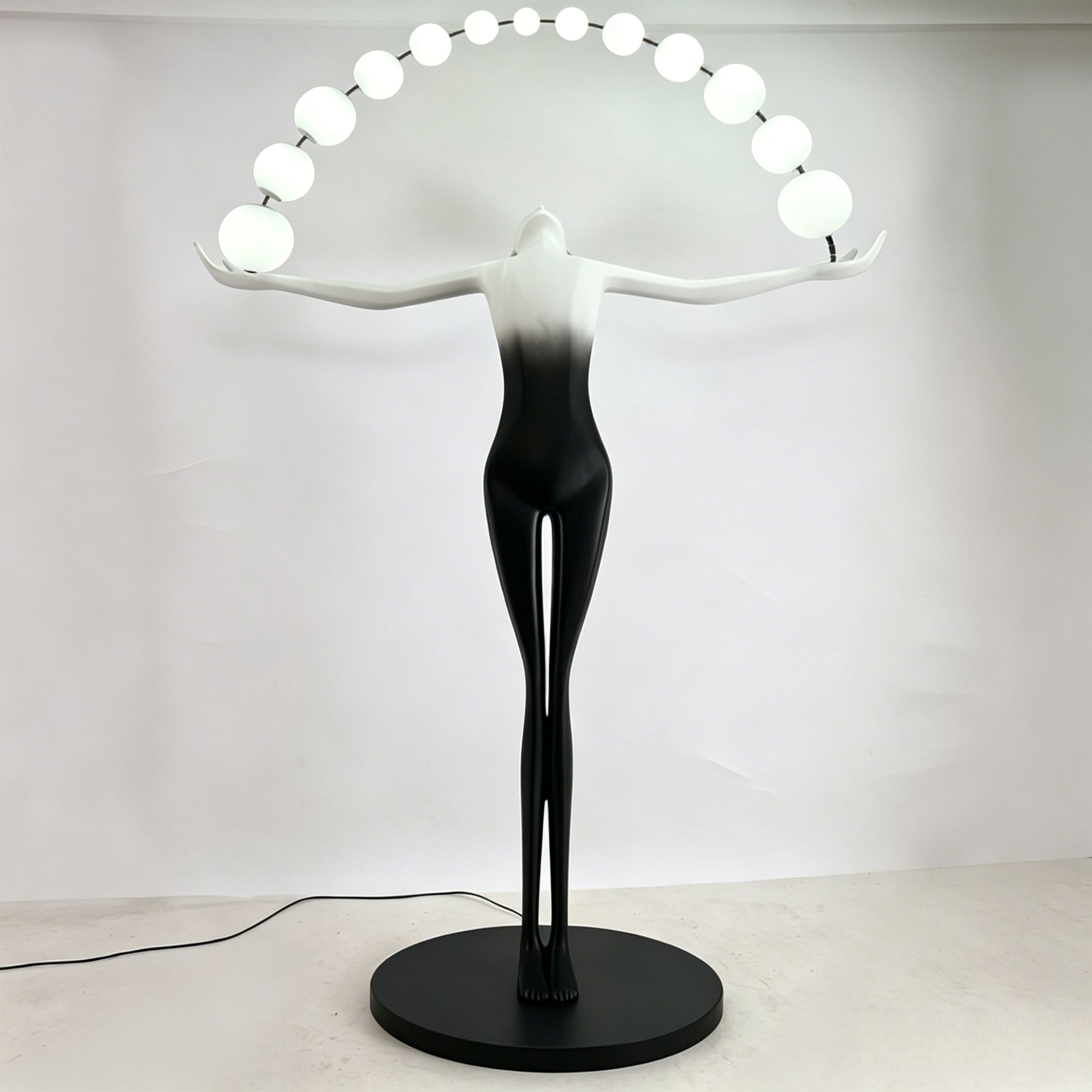 A modern decorative sculpture of a stylized female figure in black and white, with a curved string of glowing white globe lights arching above her head.Place it in the living room, hotel or villa, and it will have an artistic touch.